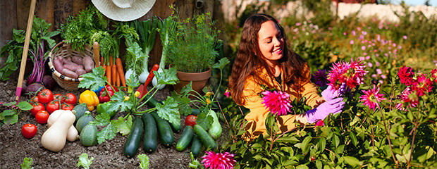 Woman taking care of flowers next to vegetable display.